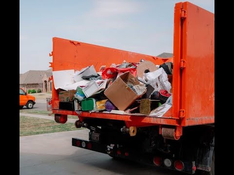 Orange dump truck loaded with household debris and clutter in a driveway for Junk removal services kent wa